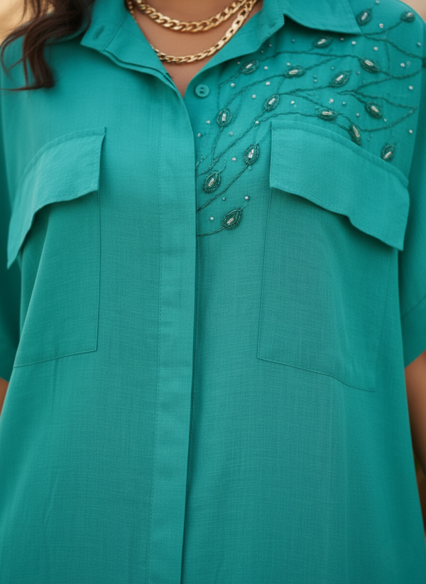 Close-up of embroidered detail and chest pockets on teal shirt dress
