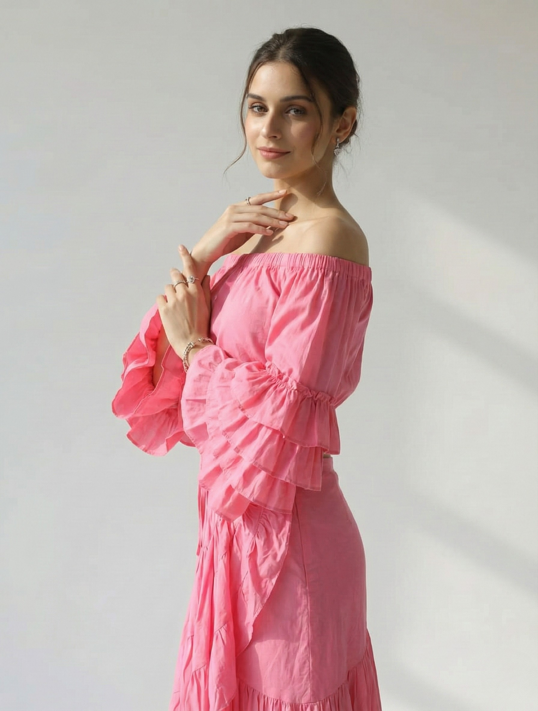 Close-up shot of the model wearing the pink off-shoulder top, detailing the fabric texture and the volume of the ruffled sleeves.