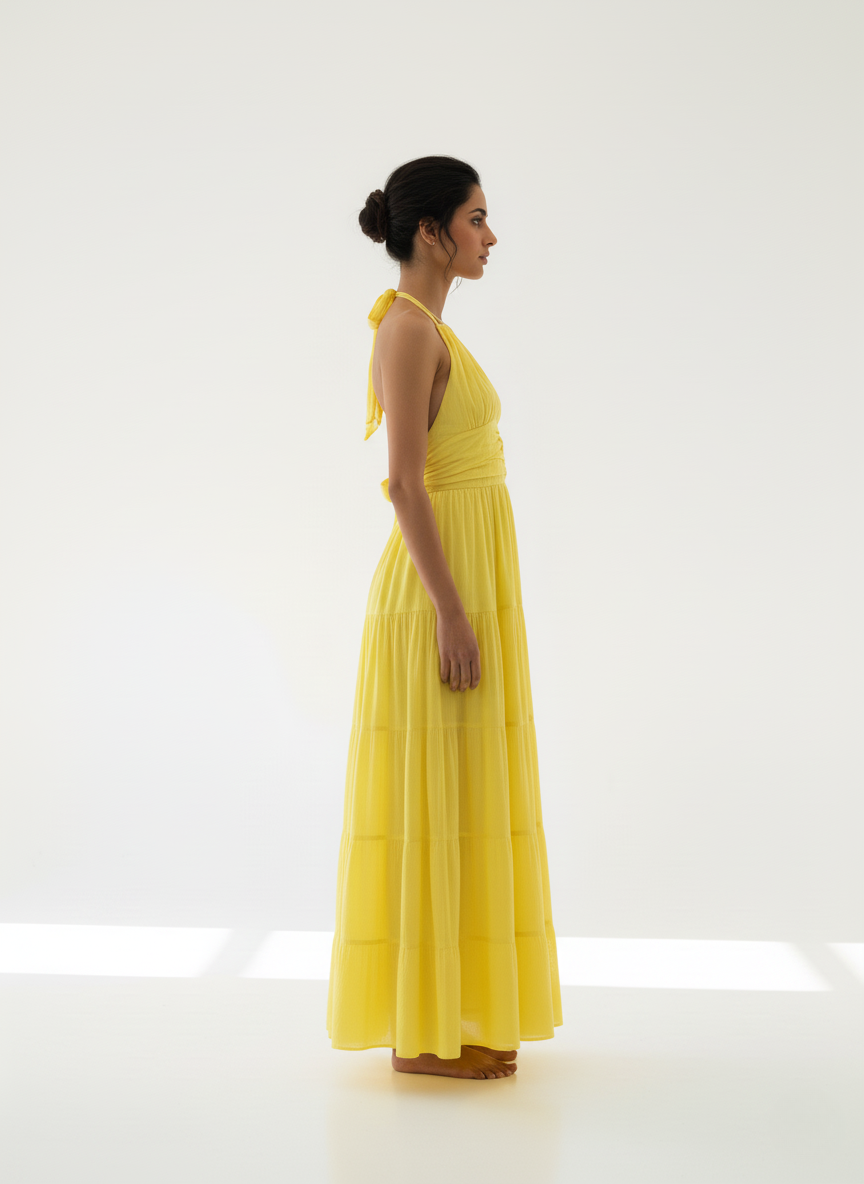 Woman in sunbeam yellow halter tiered maxi dress, side profile