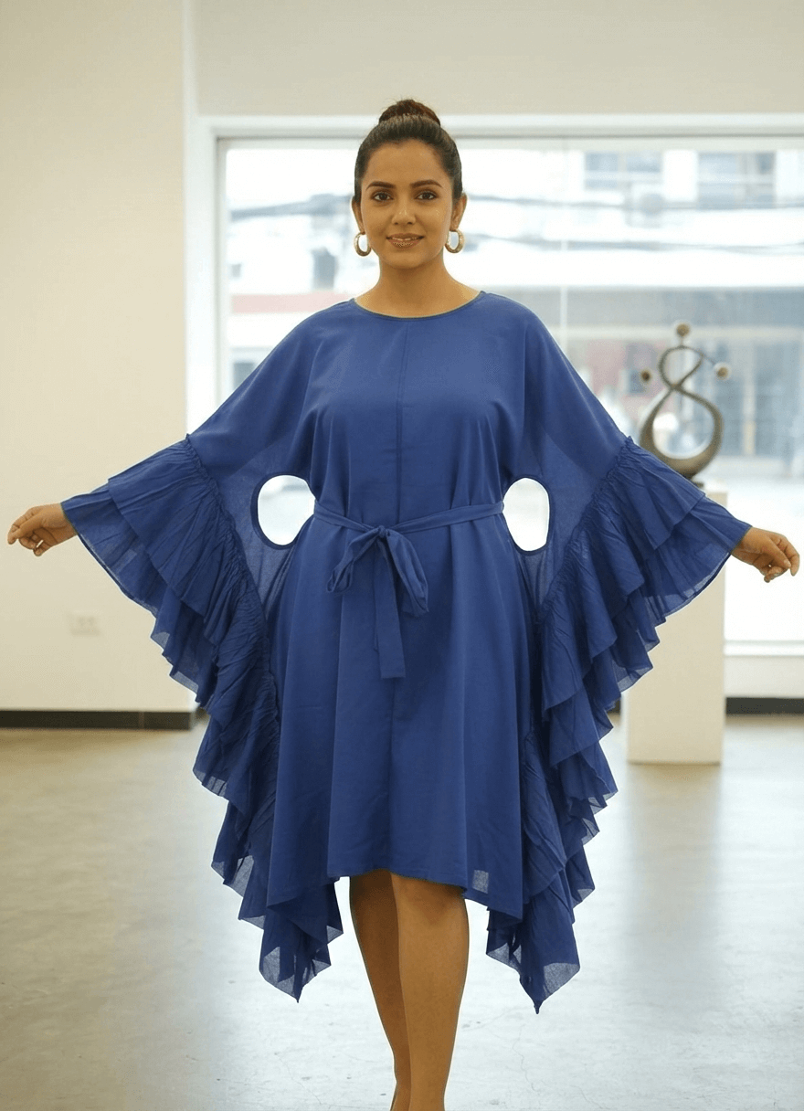 Woman posing in a blue butterfly sleeve dress showing side cut-out details and knee-length asymmetric hem.