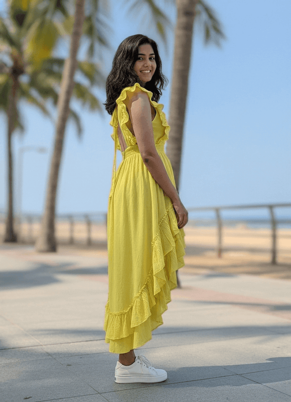 Woman in a yellow dress standing on a beach with palm trees in the background