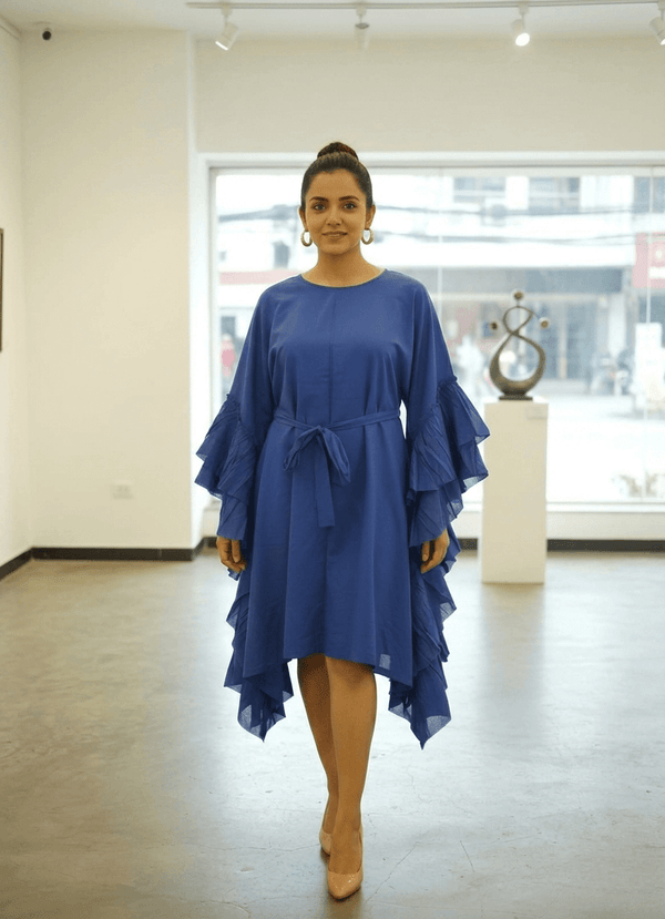 Model wearing a royal blue knee-length cotton dress with dramatic ruffle sleeves and tie-up waist.