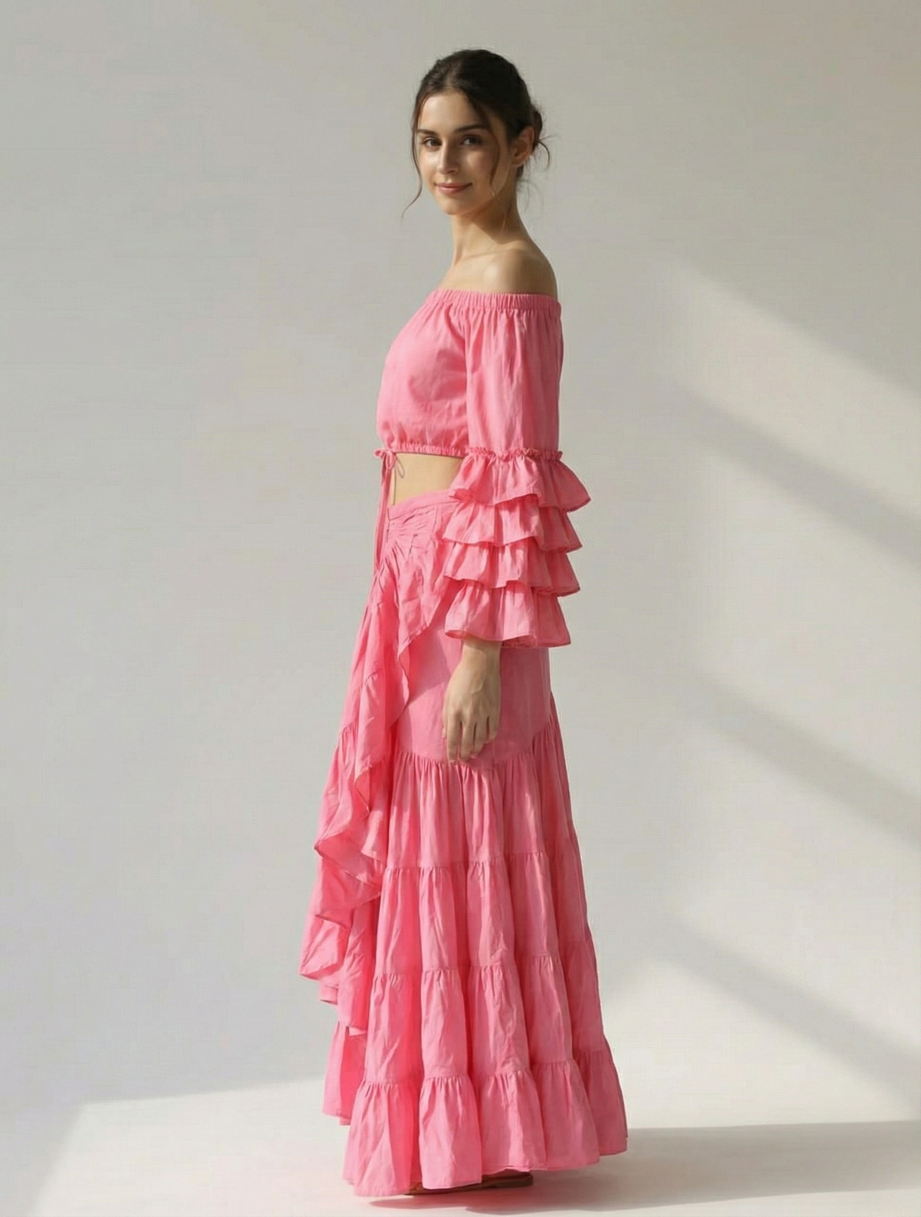 Side profile of a woman wearing a pink bohemian skirt set, highlighting the triple-tiered bell sleeves on the top and the ruffle detailing on the skirt's slit.