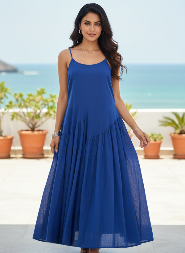Woman in royal sapphire blue flowy maxi dress, full front view, smiling on balcony overlooking the sea